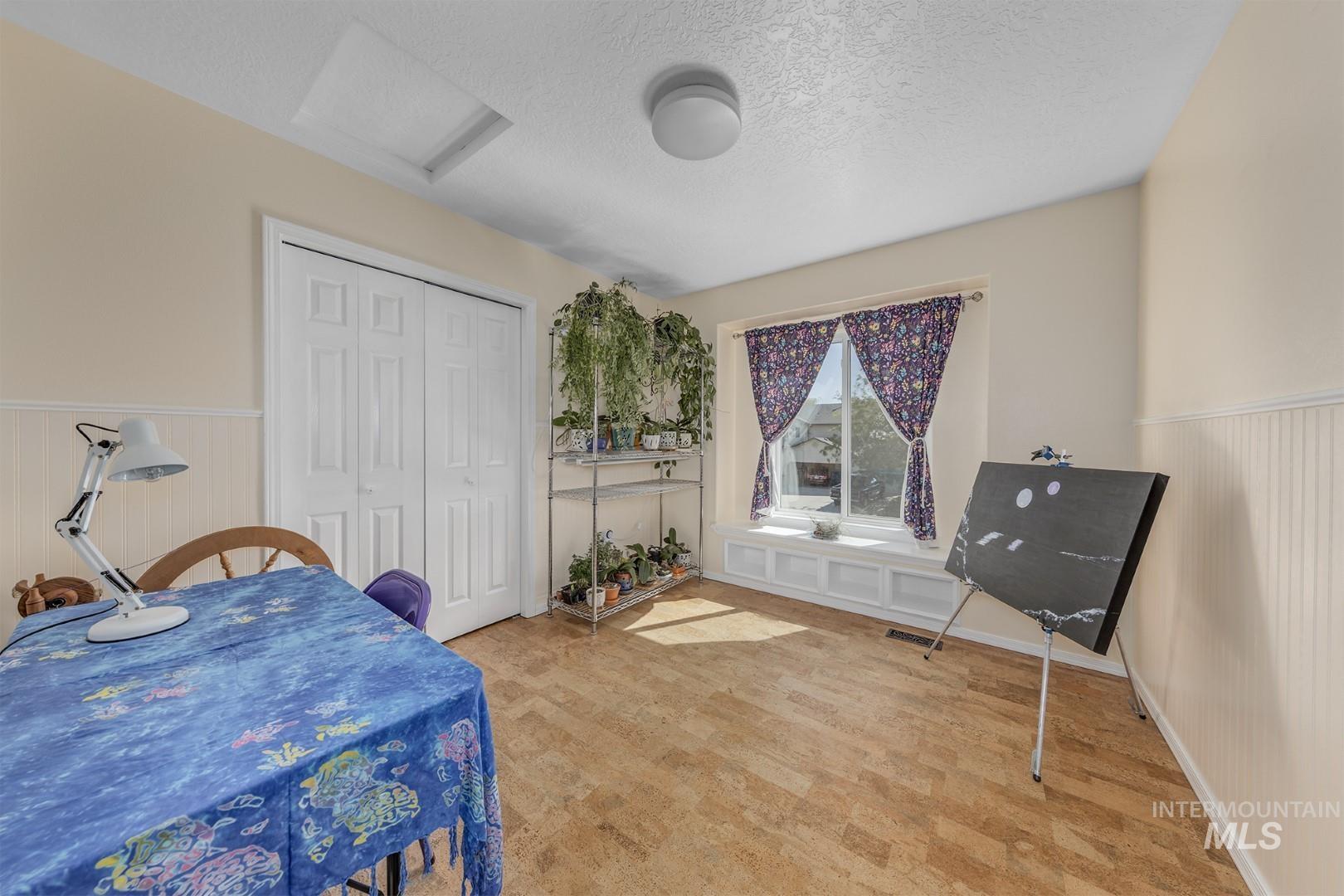 Dining area with a wainscoted wall, attic access, a textured ceiling, and light carpet