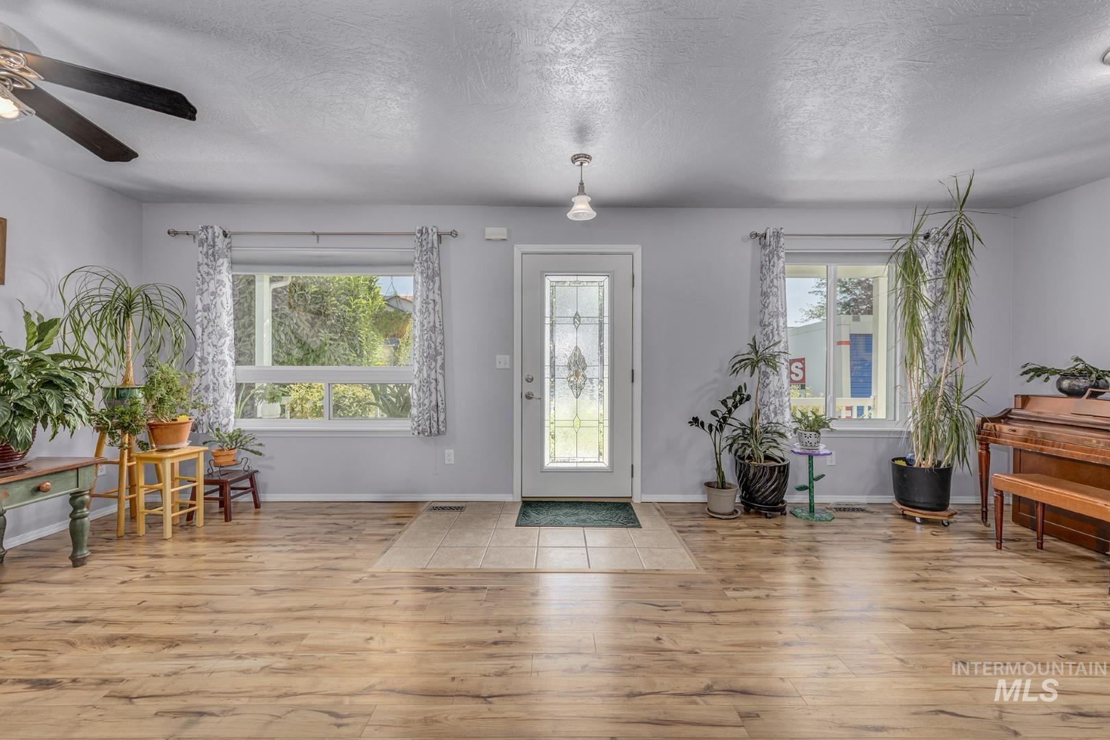 Foyer entrance featuring a textured ceiling, healthy amount of natural light, light wood-style flooring, and ceiling fan