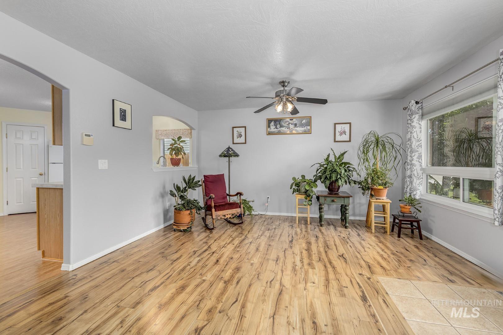 Living area featuring arched walkways, light wood-type flooring, and a ceiling fan