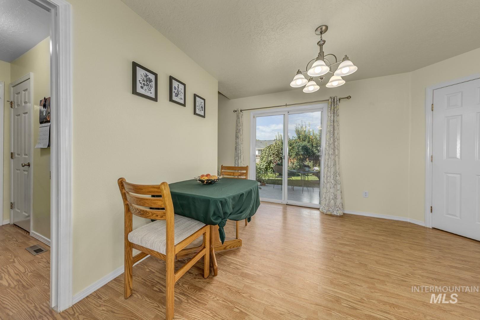 Dining area featuring light wood finished floors, a chandelier, and a textured ceiling