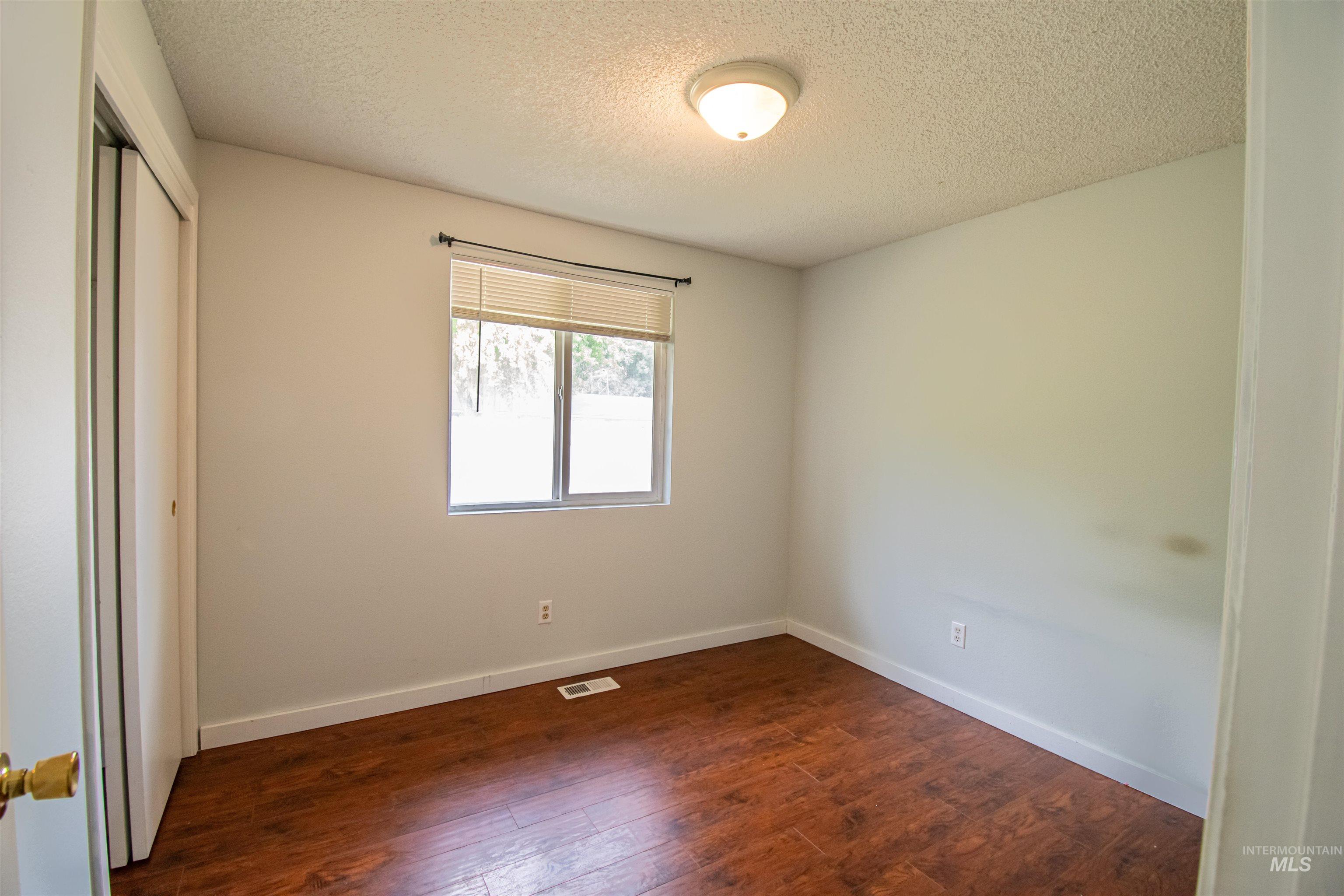 Unfurnished bedroom with a closet, dark wood-type flooring, and a textured ceiling