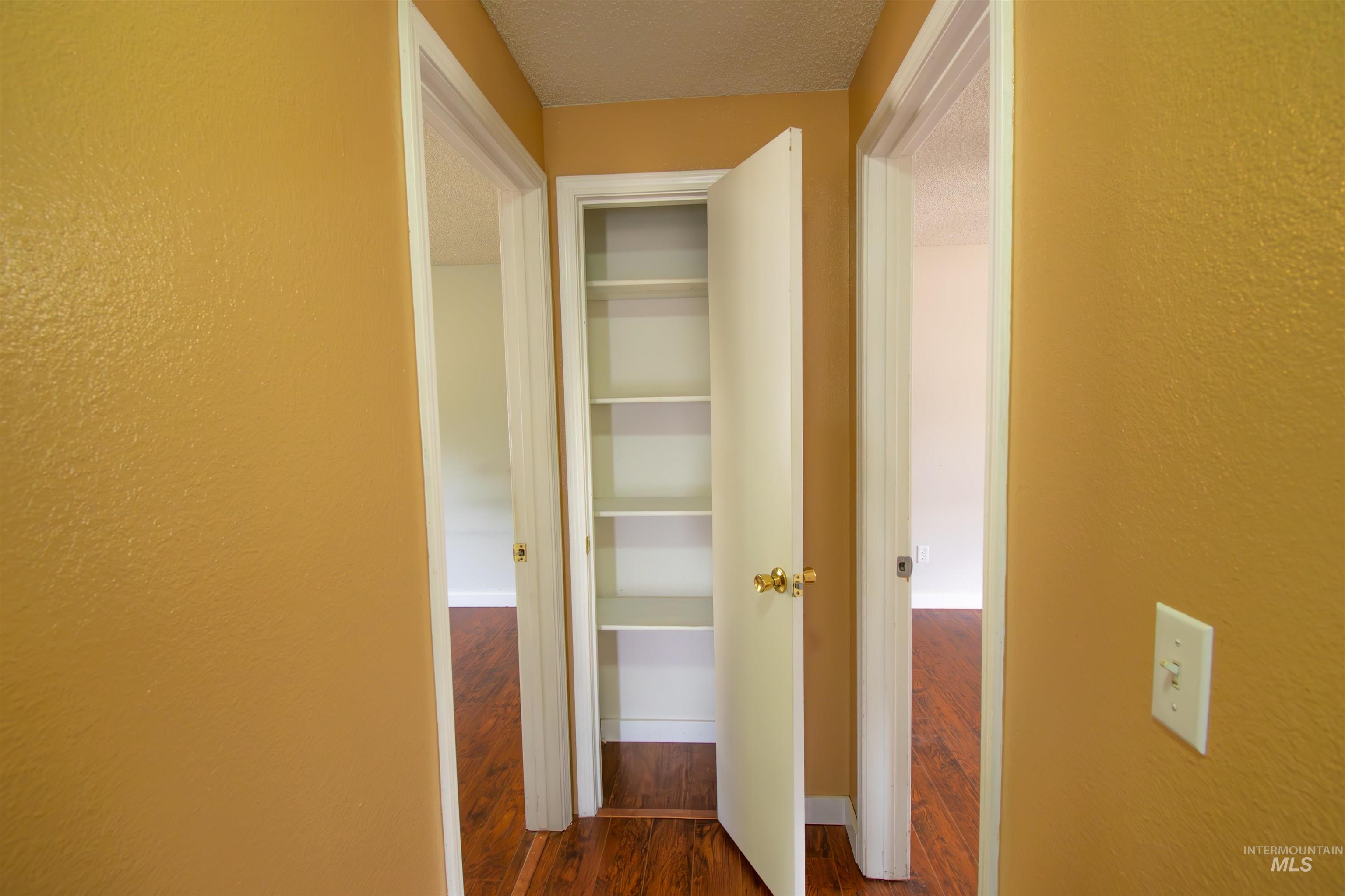 Corridor with dark wood finished floors, a textured ceiling, and a textured wall