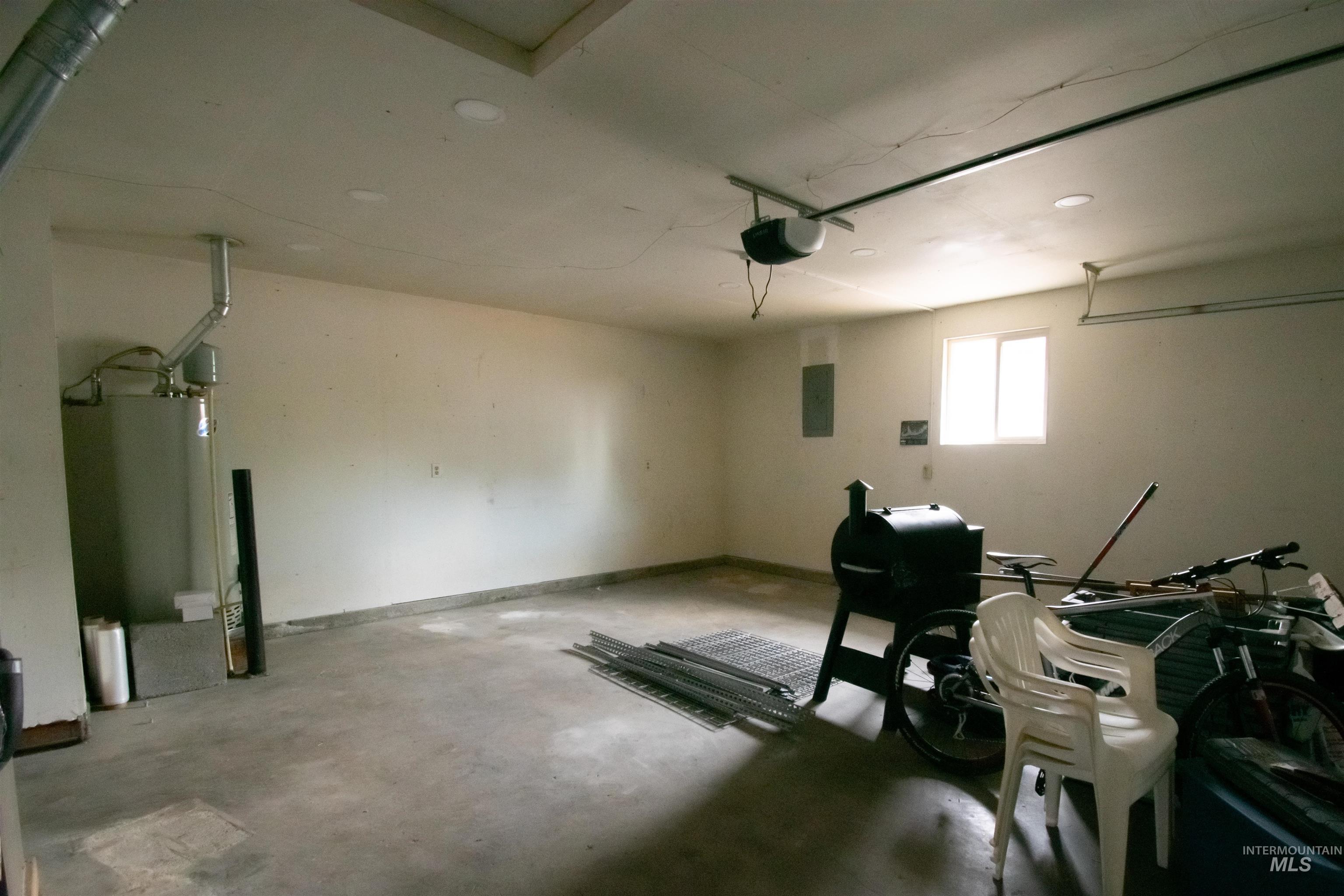 Garage with electric panel, a garage door opener, and water heater