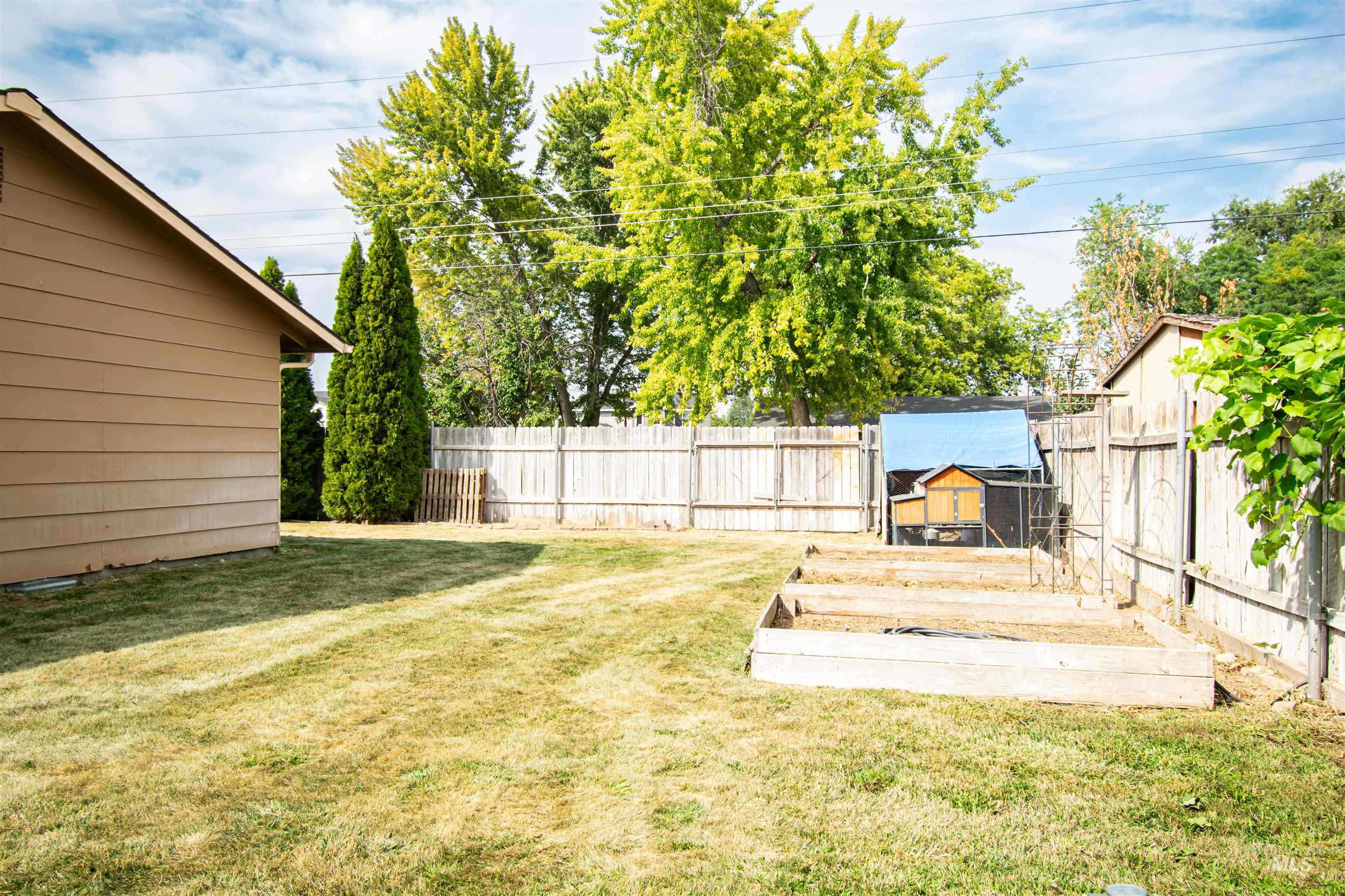 Fenced backyard with an outbuilding and a vegetable garden