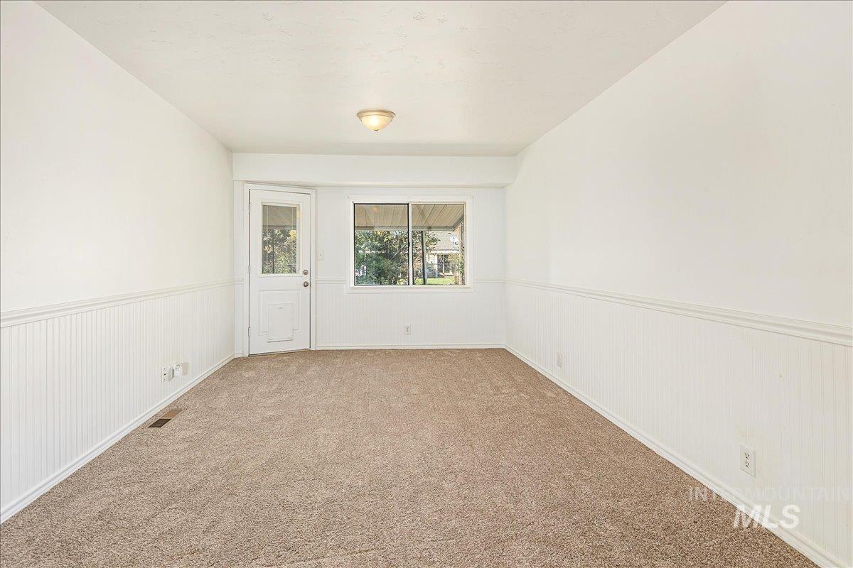 Carpeted empty room featuring a wainscoted wall