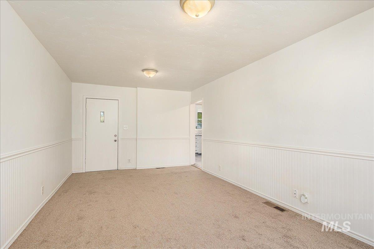 Carpeted empty room featuring a wainscoted wall