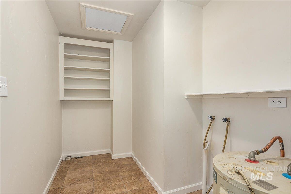 Spacious closet featuring water heater and attic access