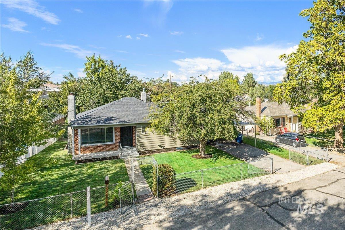 View of front of home with a chimney, a fenced front yard, brick siding, and a shingled roof