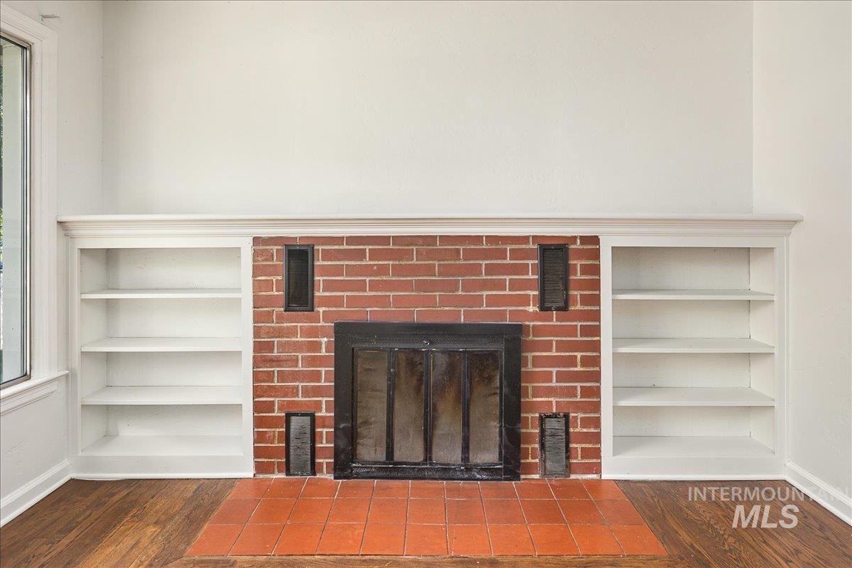 Detailed view of built in shelves, wood finished floors, and a fireplace