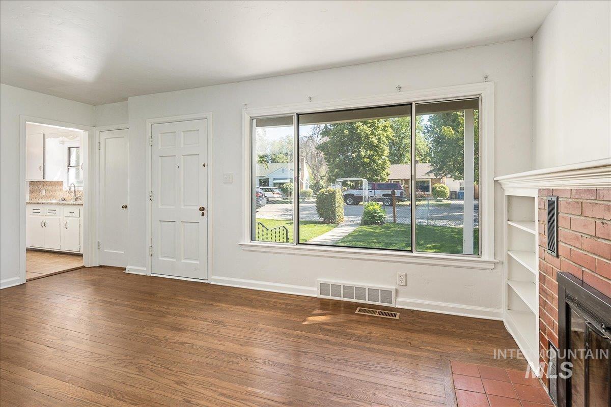 Unfurnished living room featuring dark wood-style floors and a fireplace
