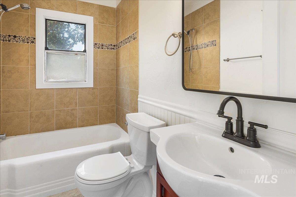 Bathroom featuring shower / bathtub combination, vanity, and wainscoting