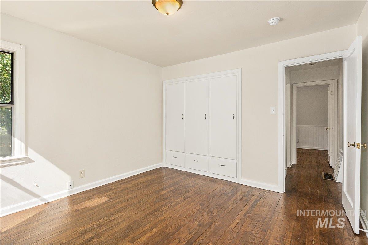 Unfurnished bedroom featuring dark wood finished floors and a closet