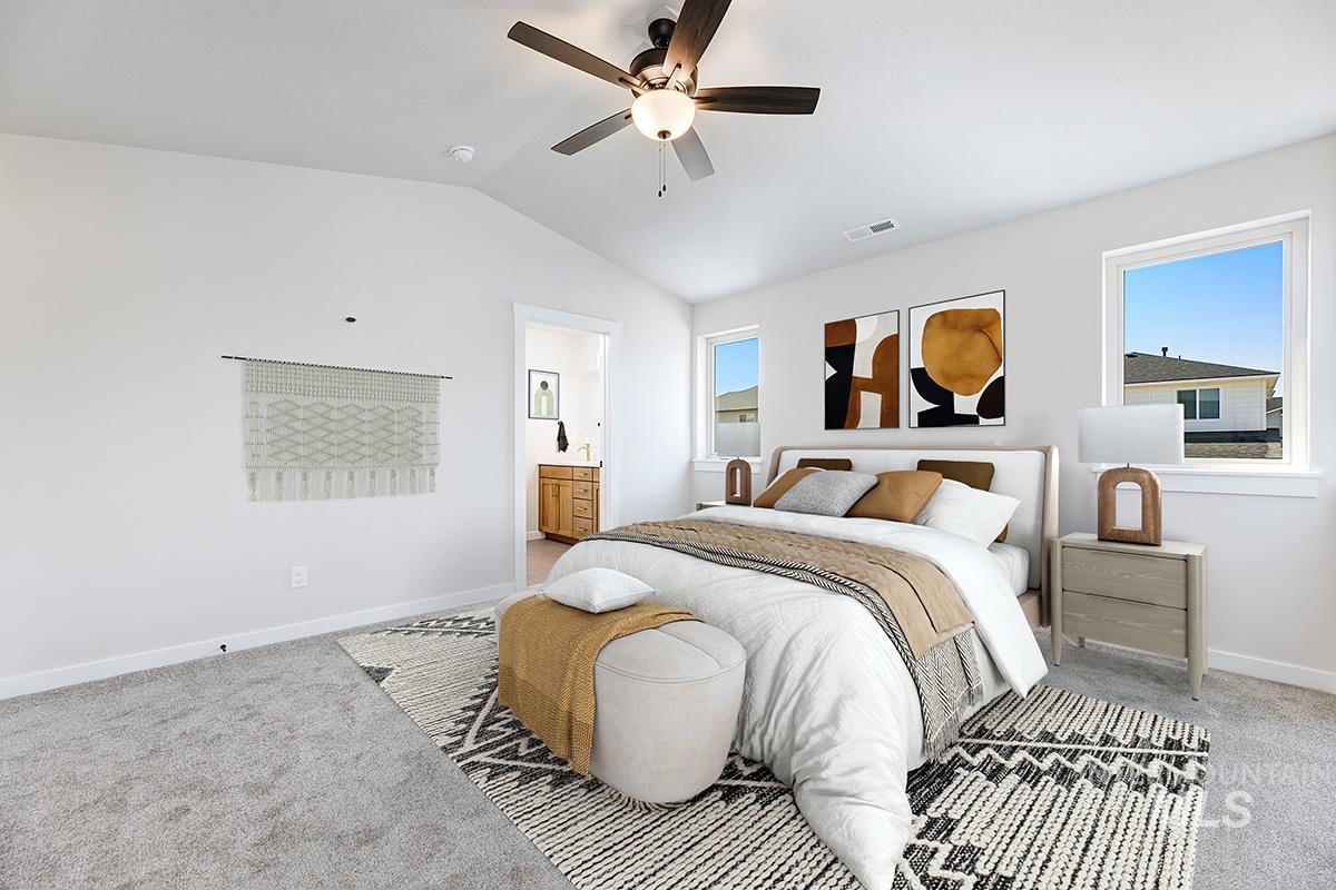 Bedroom with carpet floors, vaulted ceiling, connected bathroom, and a ceiling fan