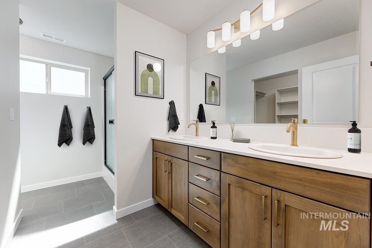 Bathroom with double vanity, a stall shower, and dark tile patterned floors