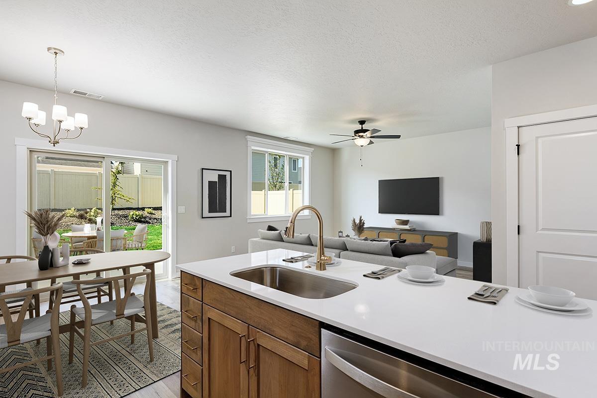 Kitchen with brown cabinets, light wood finished floors, dishwasher, a textured ceiling, and open floor plan