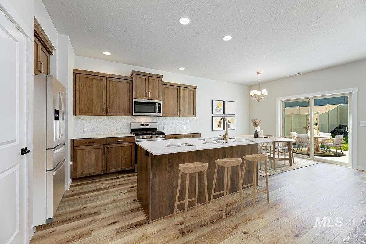 Kitchen with a center island with sink, a breakfast bar, tasteful backsplash, appliances with stainless steel finishes, and pendant lighting