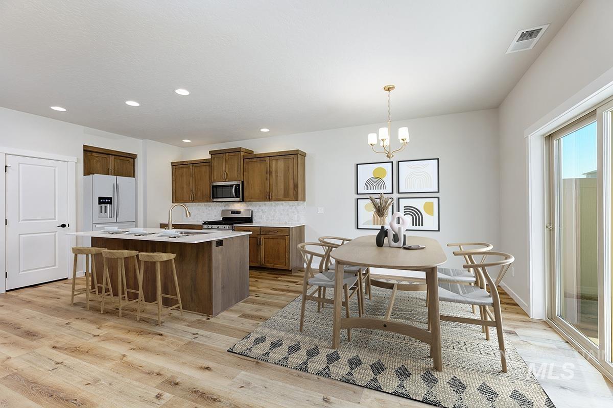 Kitchen featuring a kitchen island with sink, tasteful backsplash, a kitchen breakfast bar, light wood finished floors, and a chandelier