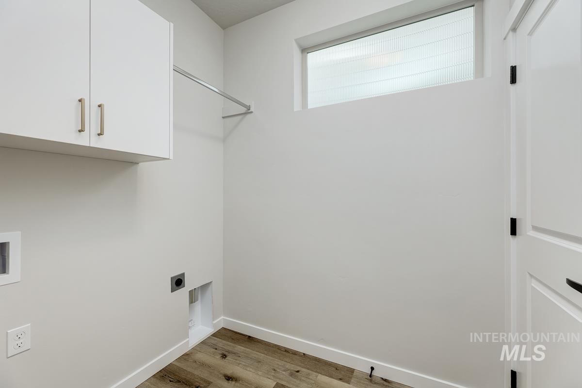 Laundry area with light wood-type flooring, cabinet space, electric dryer hookup, and hookup for a washing machine