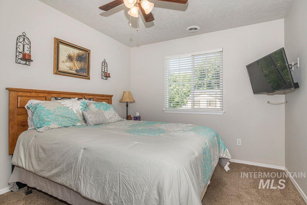 Carpeted bedroom with a ceiling fan