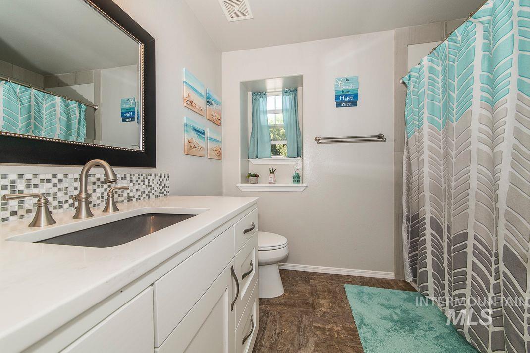 Full bath with vanity and tasteful backsplash