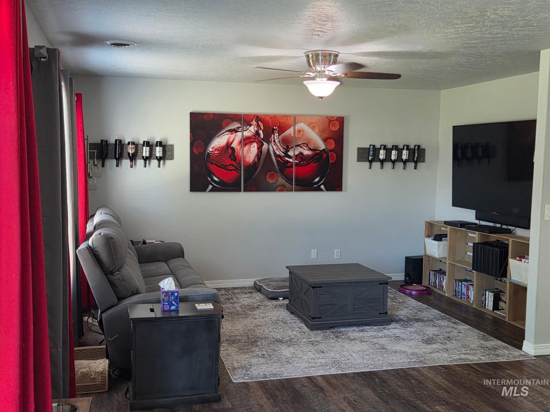 Living room with wood finished floors, a ceiling fan, and a textured ceiling