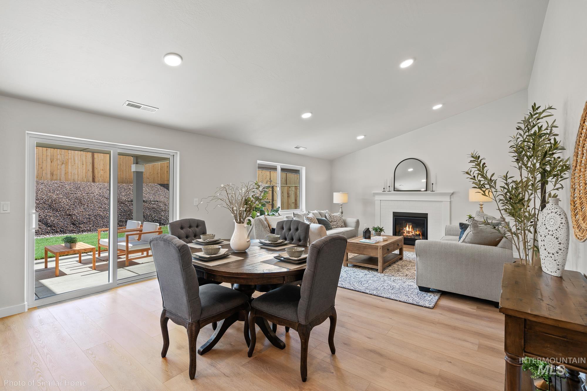 Dining space with a glass covered fireplace, healthy amount of natural light, recessed lighting, lofted ceiling, and light wood-type flooring