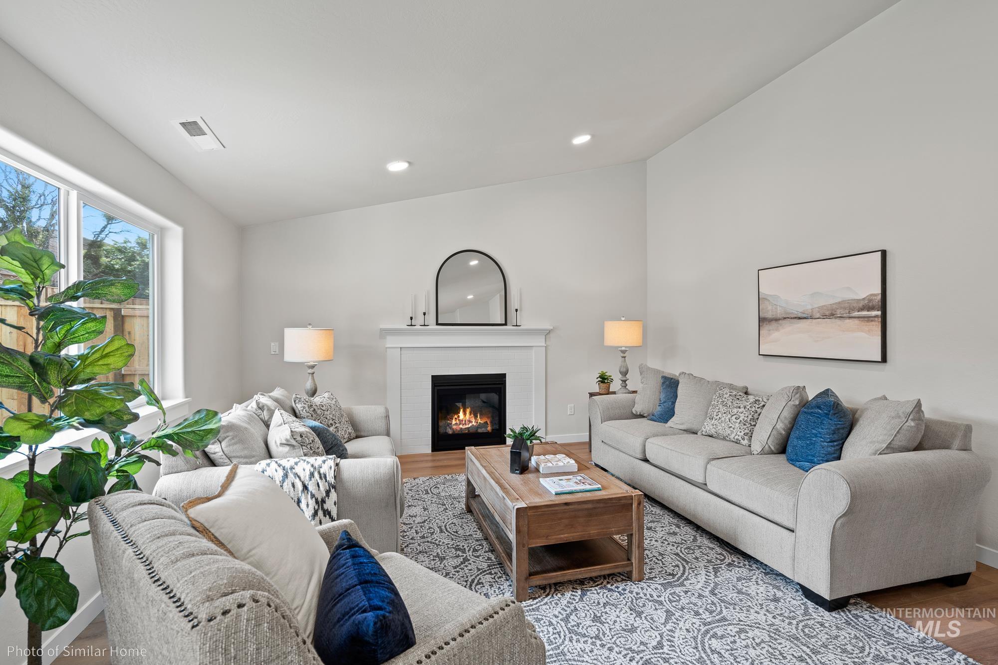 Living room with wood finished floors, a glass covered fireplace, and recessed lighting