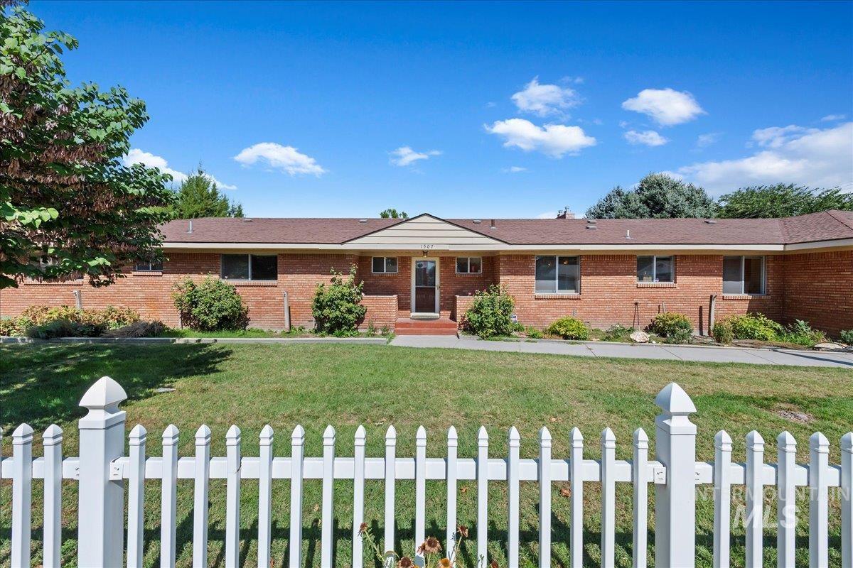 Single story home with a front lawn and brick siding