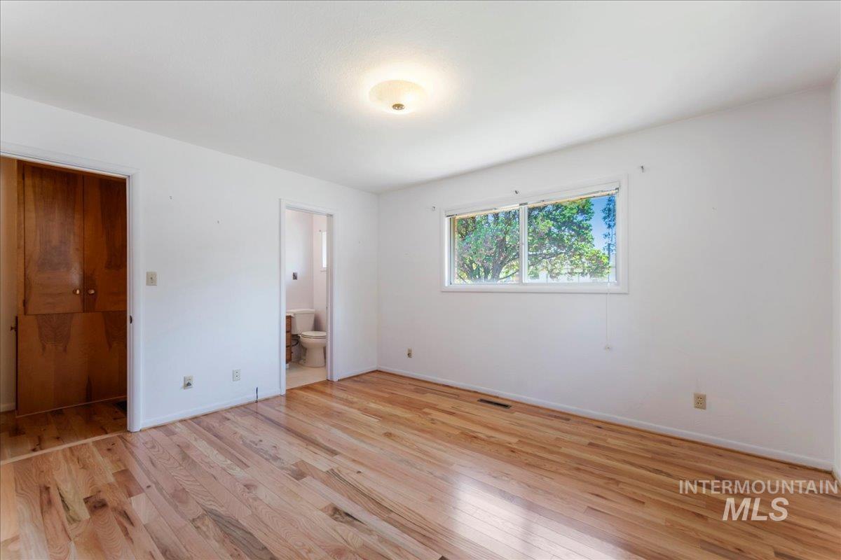Unfurnished bedroom with light wood-type flooring and connected bathroom