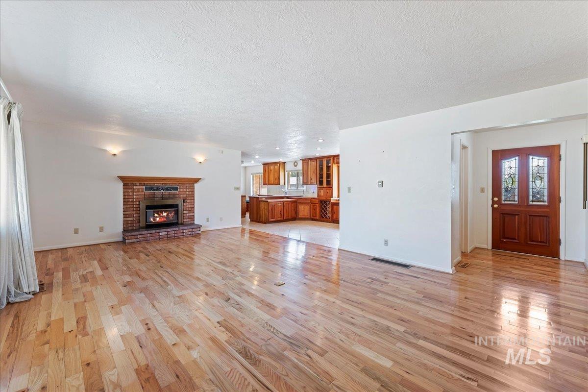 Unfurnished living room featuring light wood-style flooring, a fireplace, a textured ceiling, and healthy amount of natural light