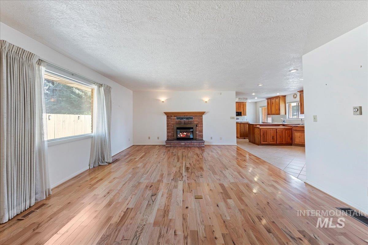 Unfurnished living room featuring a fireplace, light wood-style flooring, and a textured ceiling