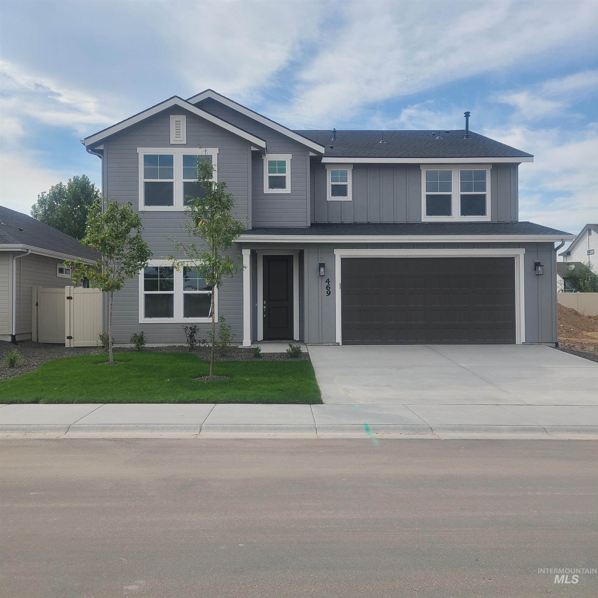 Traditional home featuring a garage, concrete driveway, a gate, and board and batten siding