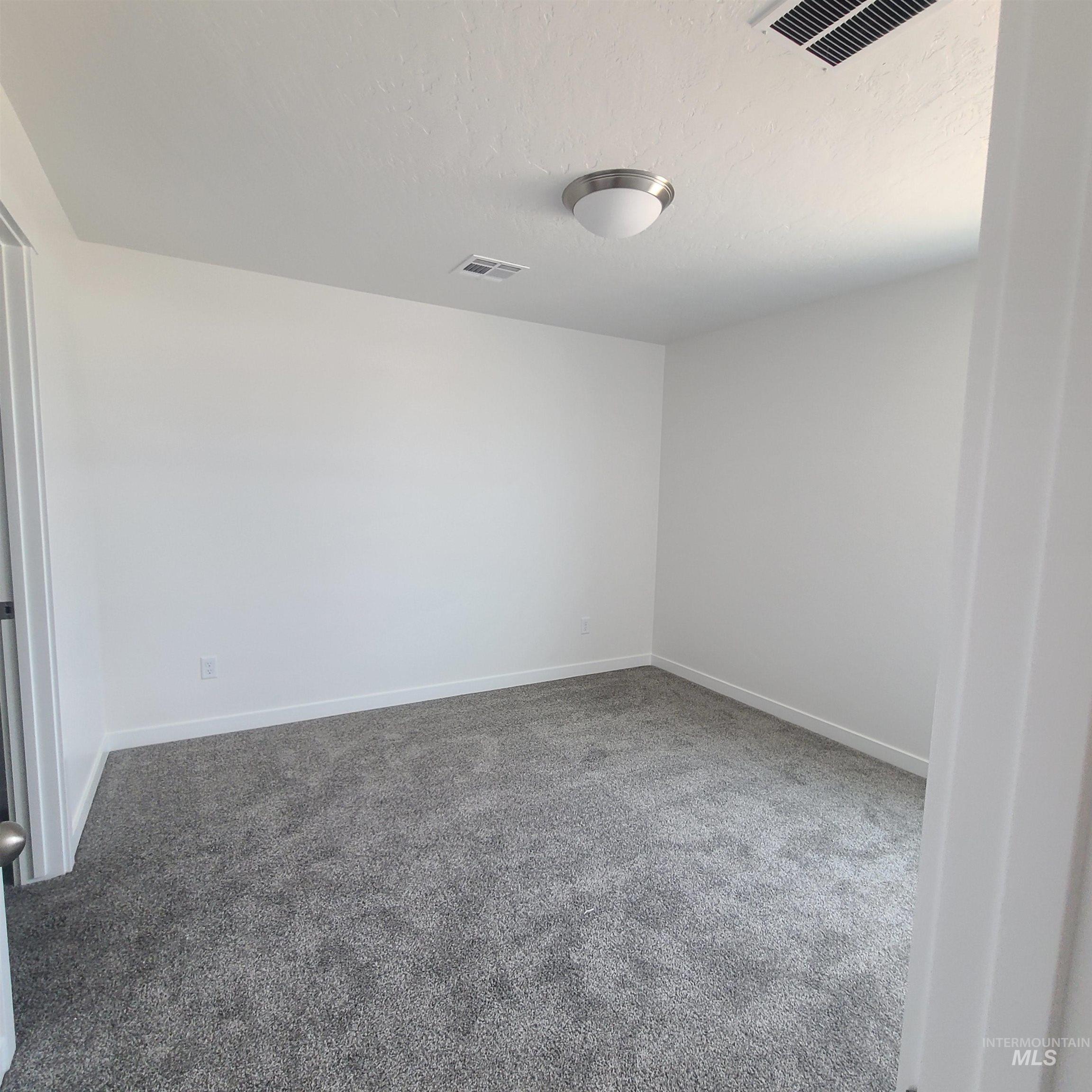 Spare room with light carpet and a textured ceiling