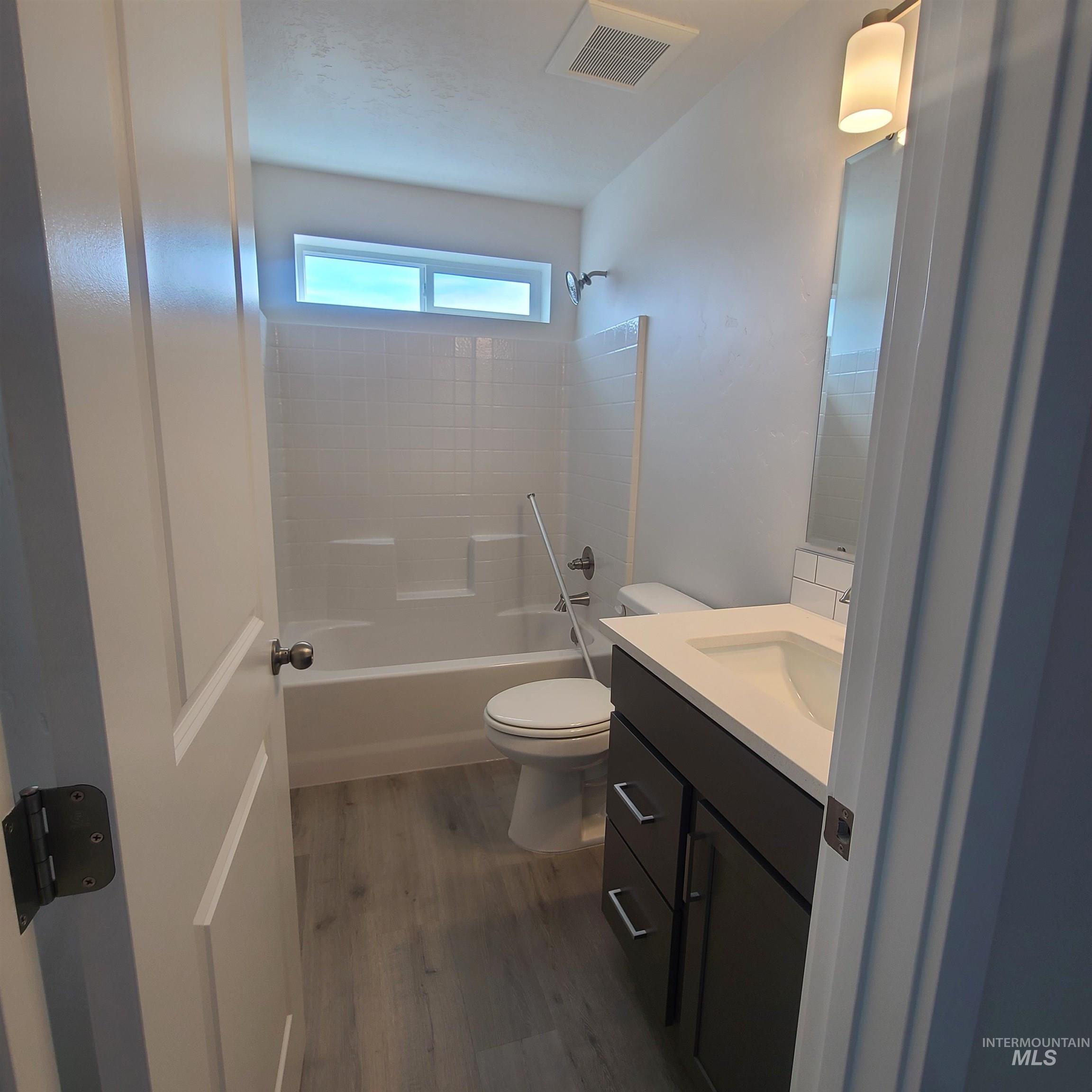 Full bath with shower / tub combination, dark wood-type flooring, and vanity