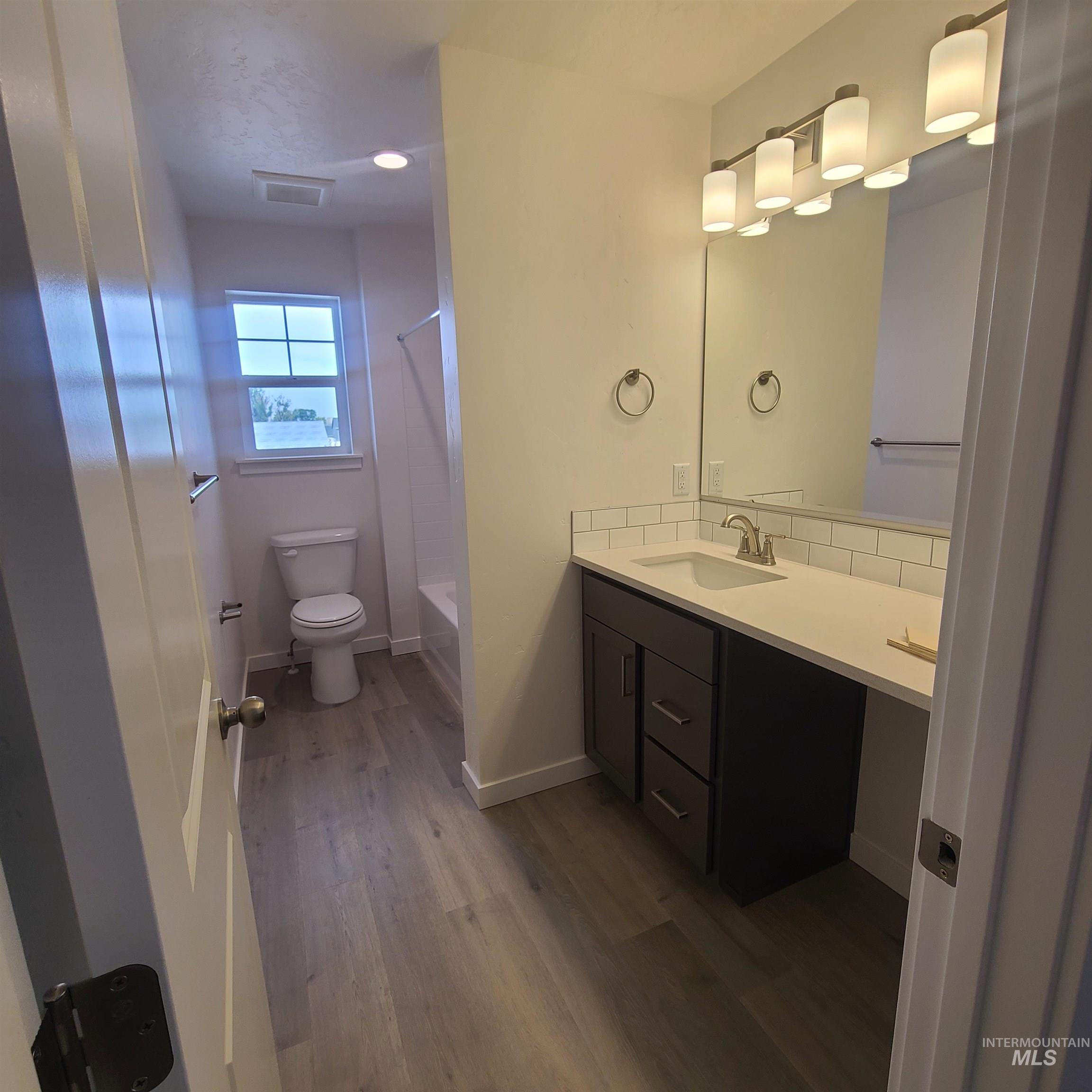 Bathroom with dark wood-style floors, shower / tub combination, and vanity