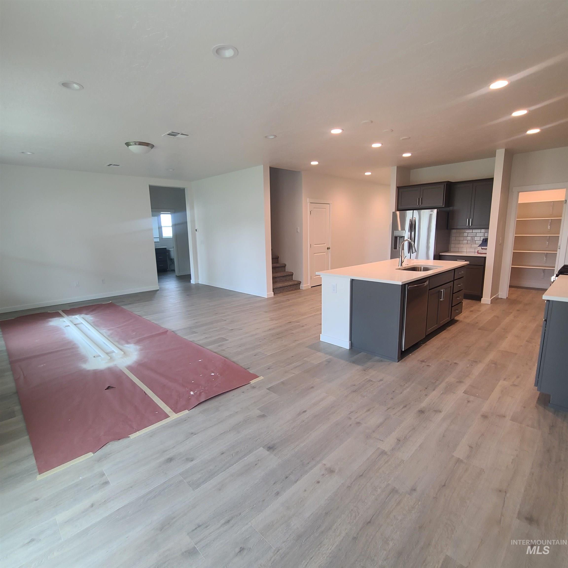 Kitchen featuring open floor plan, a center island with sink, recessed lighting, stainless steel appliances, and light wood-style floors