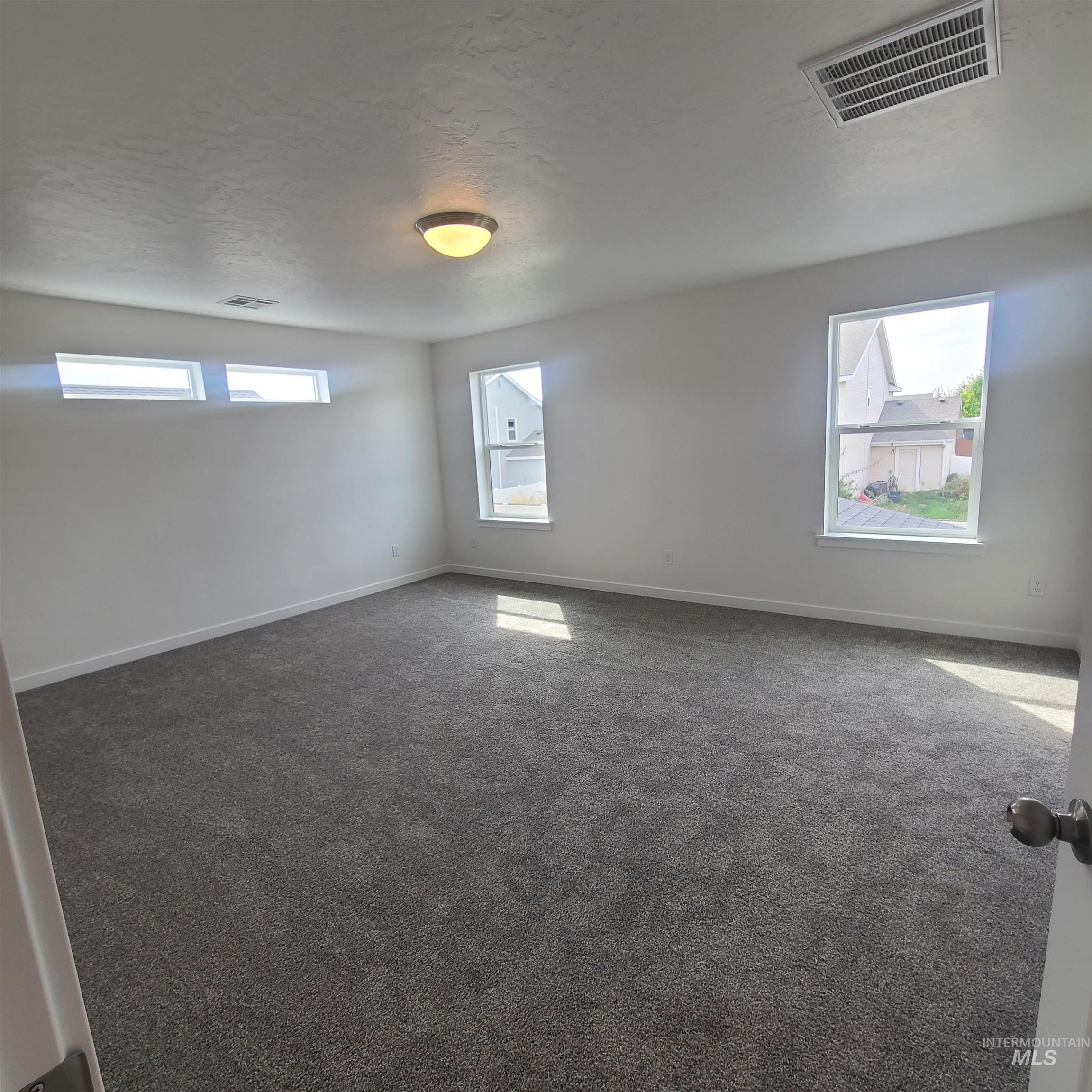 Spare room with dark colored carpet and a textured ceiling