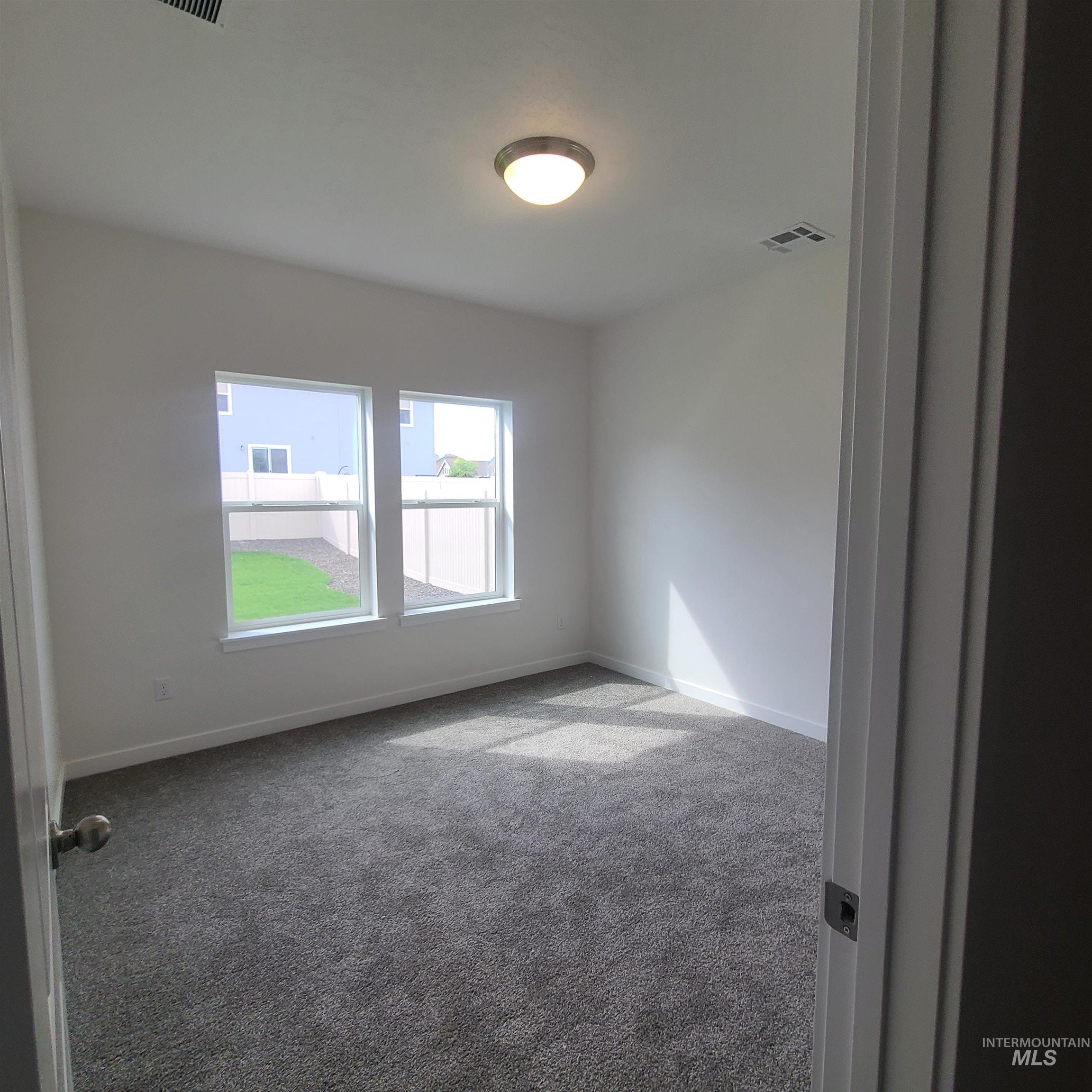 Carpeted spare room featuring baseboards