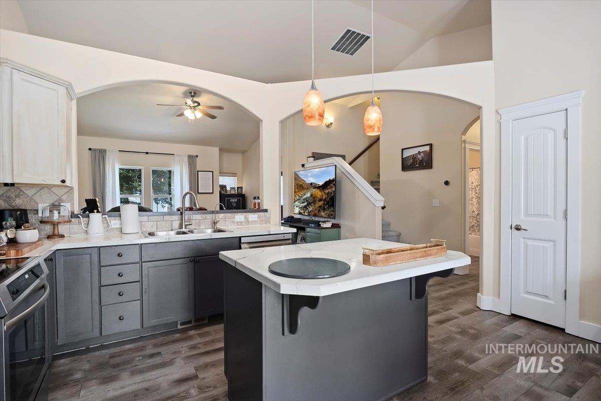 Kitchen featuring gray cabinetry, stainless steel electric stove, pendant lighting, a breakfast bar, and white cabinetry