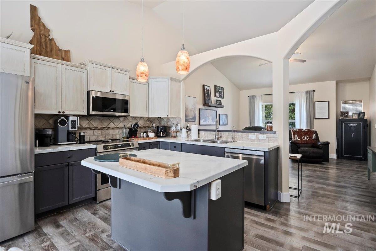 Kitchen featuring appliances with stainless steel finishes, a breakfast bar, open floor plan, a peninsula, and backsplash