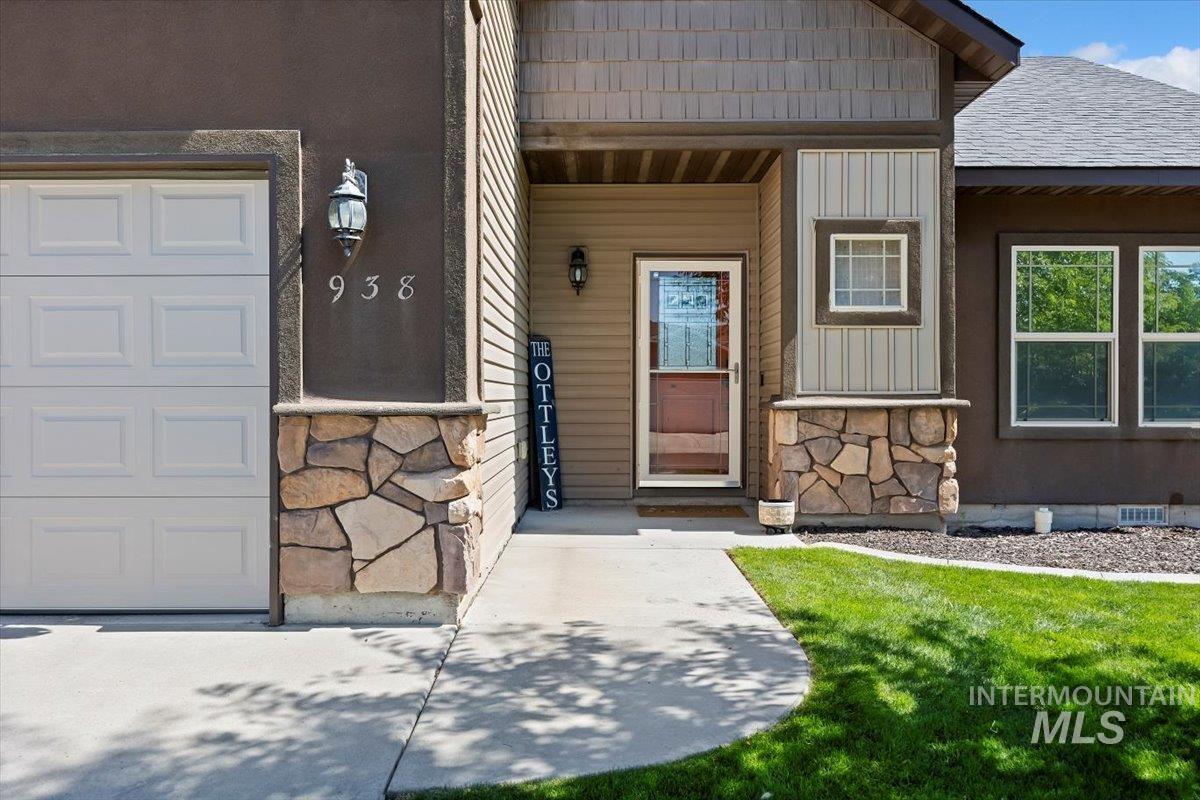Doorway to property with stone siding, covered porch, and board and batten siding