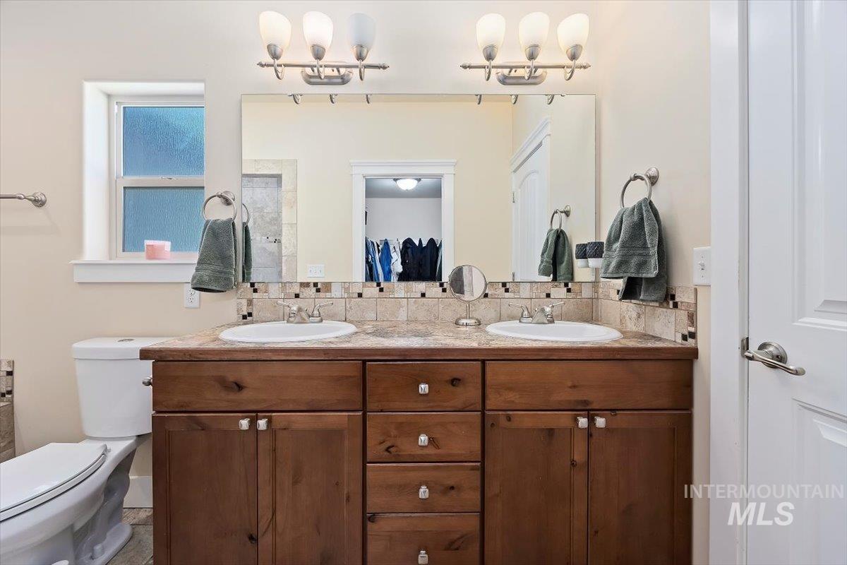 Bathroom featuring double vanity and tasteful backsplash