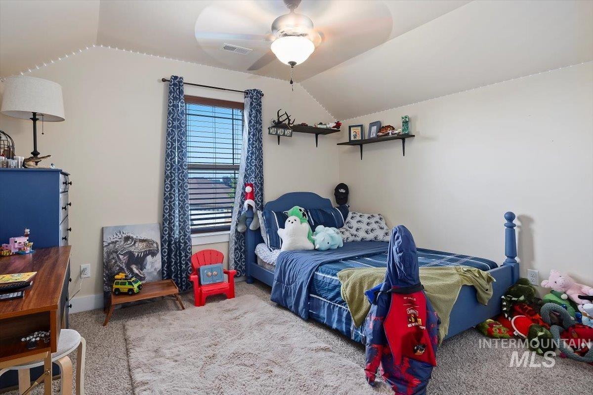 Carpeted bedroom with vaulted ceiling and a ceiling fan