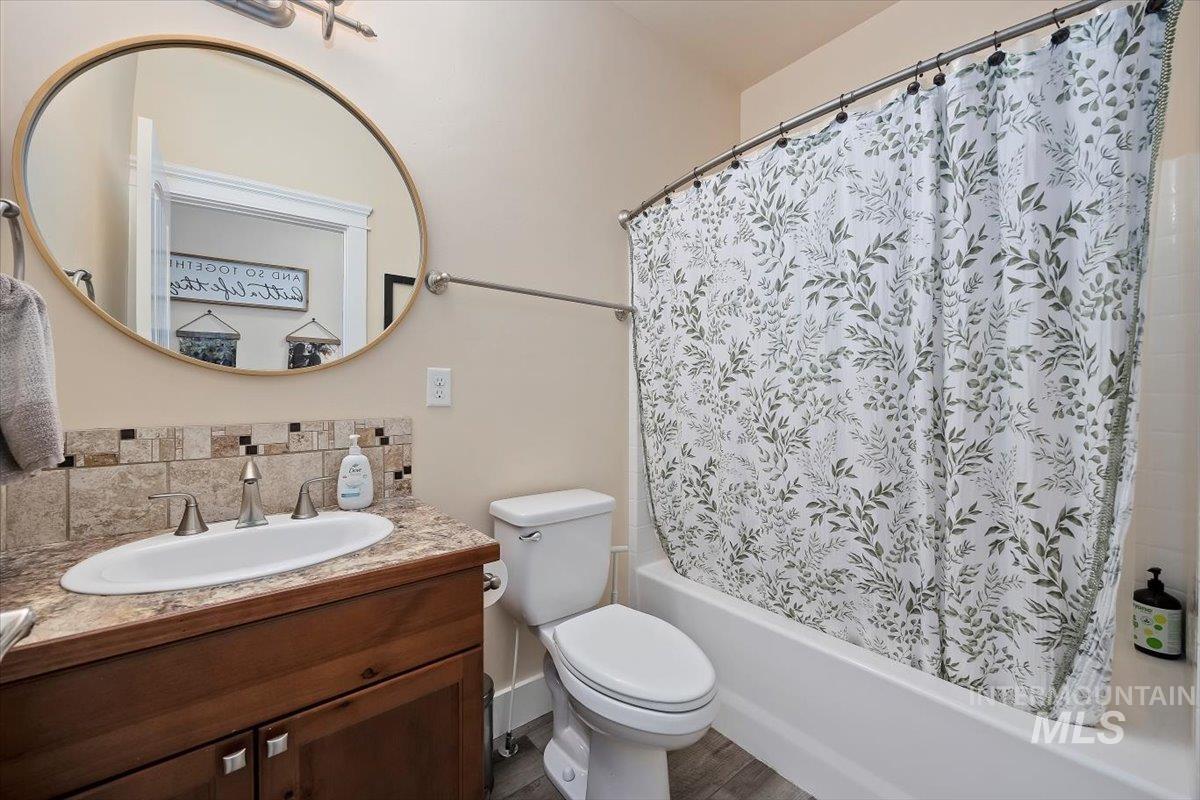 Bathroom with vanity, shower / bath combo, and backsplash