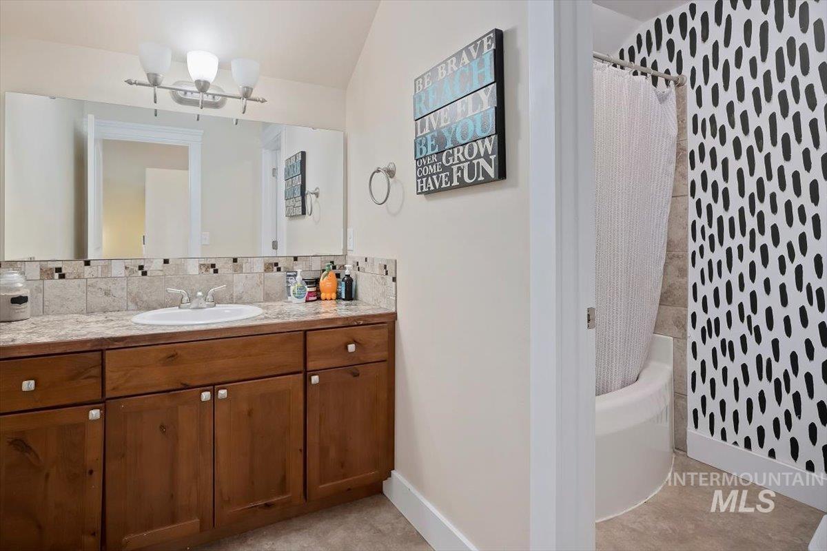 Bathroom with vanity, shower / tub combo with curtain, and decorative backsplash