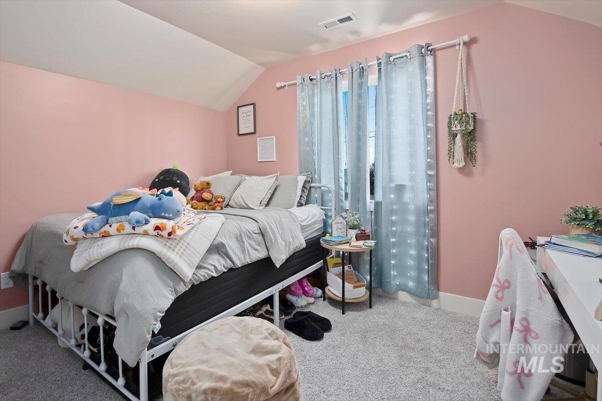 Bedroom with light colored carpet and lofted ceiling