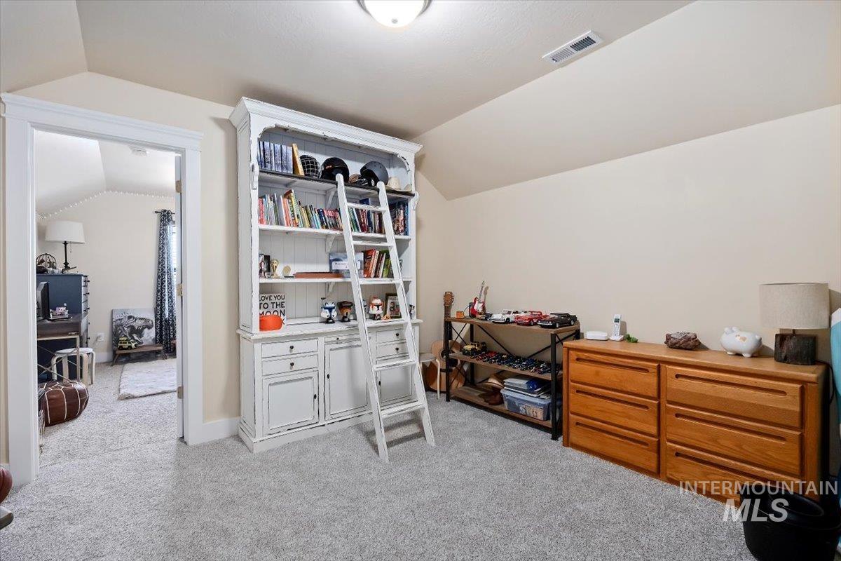 Office space featuring vaulted ceiling and light colored carpet