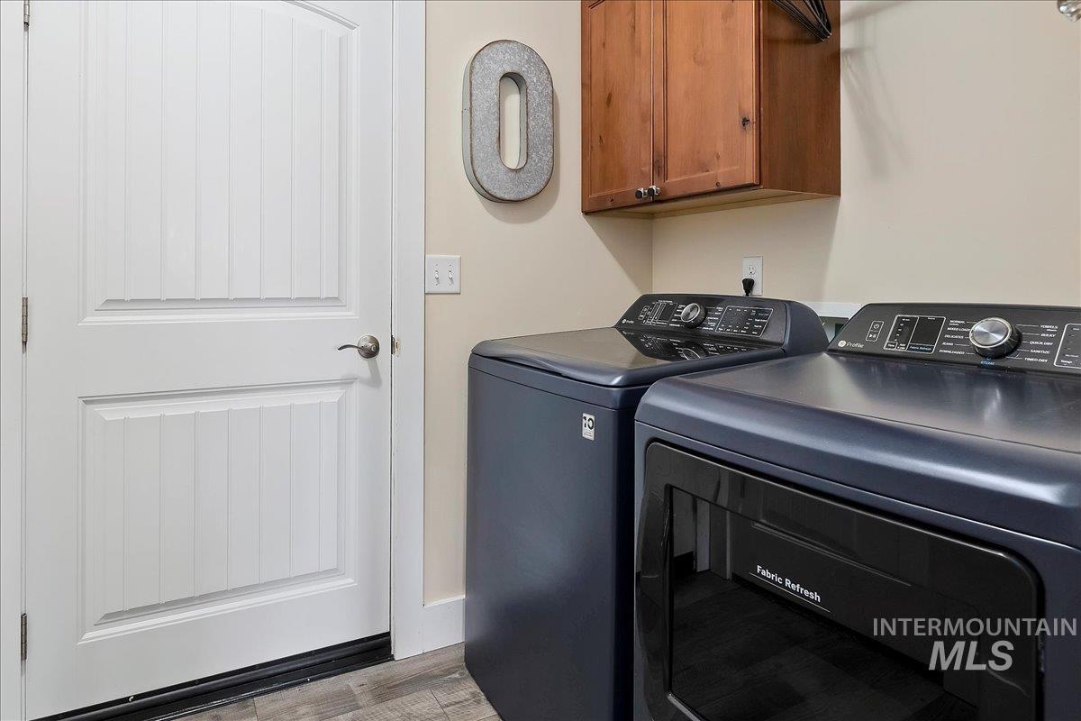 Washroom with washing machine and clothes dryer, cabinet space, and light wood-style floors