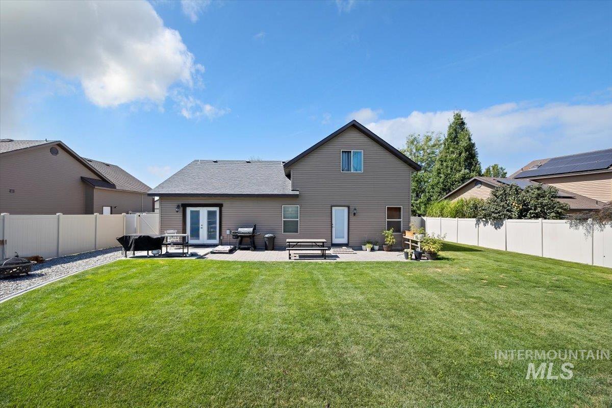 Rear view of property with a patio, a fenced backyard, and french doors