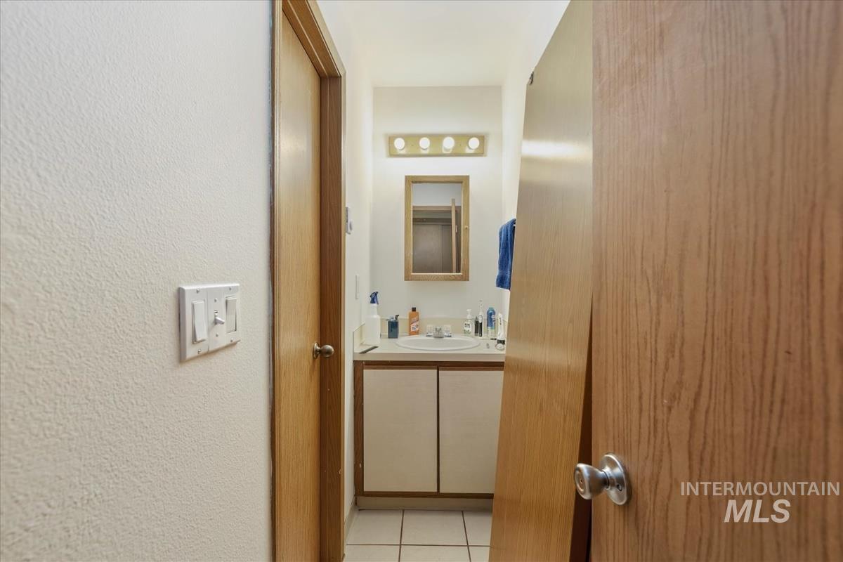 Bathroom with light tile patterned floors, vanity, and a textured wall